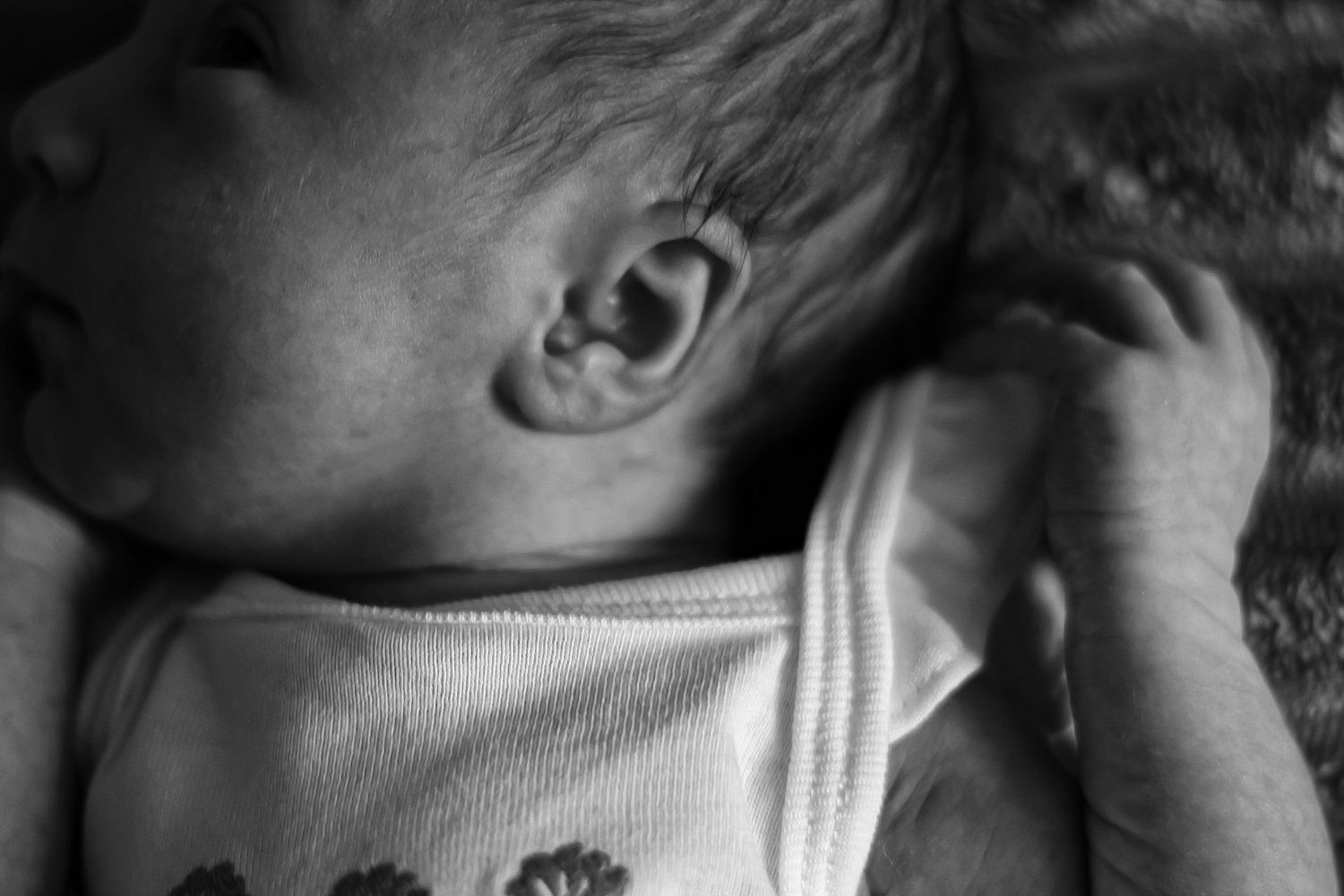 Black and white images showing sleeping infant details in soft lighting.