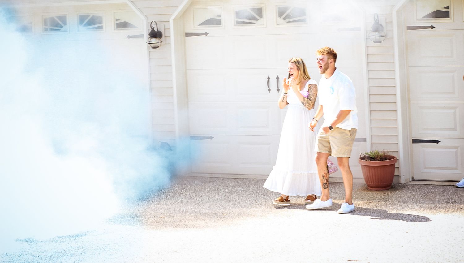 Colorful smoke effects create a dramatic scene outside a white garage with people celebrating.