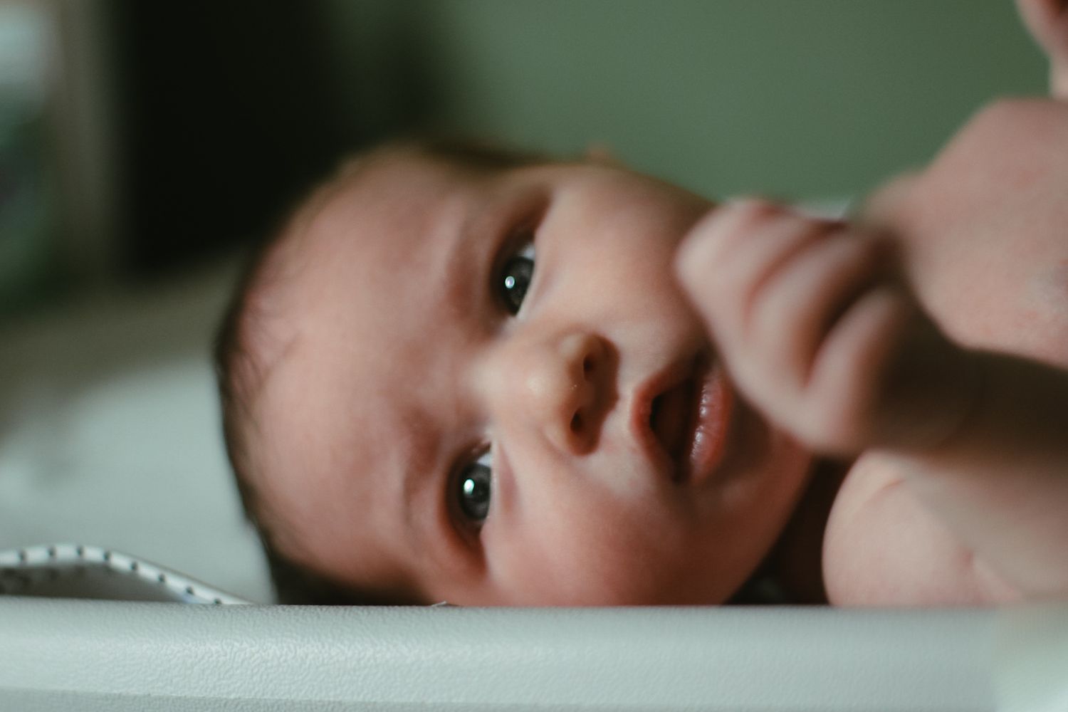 Close-up portrait of an infant laying on a soft surface.