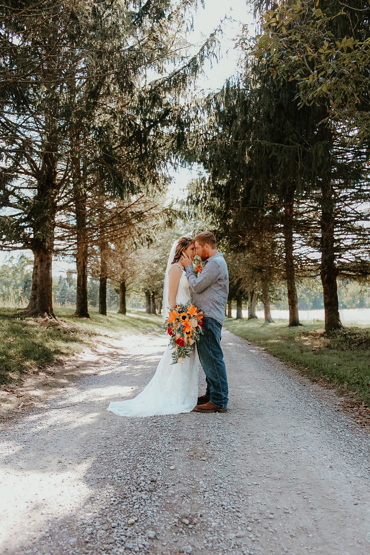 Romantic outdoor wedding photos captured along a tree-lined gravel path during golden hour.