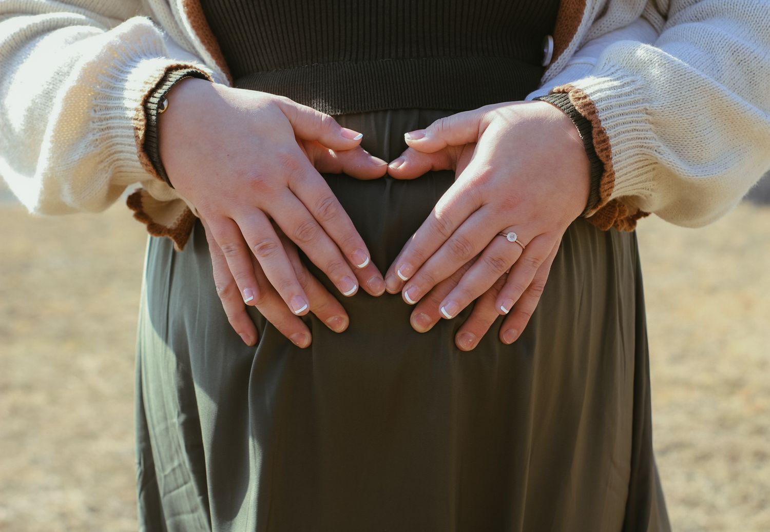 Close-up of hands wearing bracelets resting against a dark green skirt.