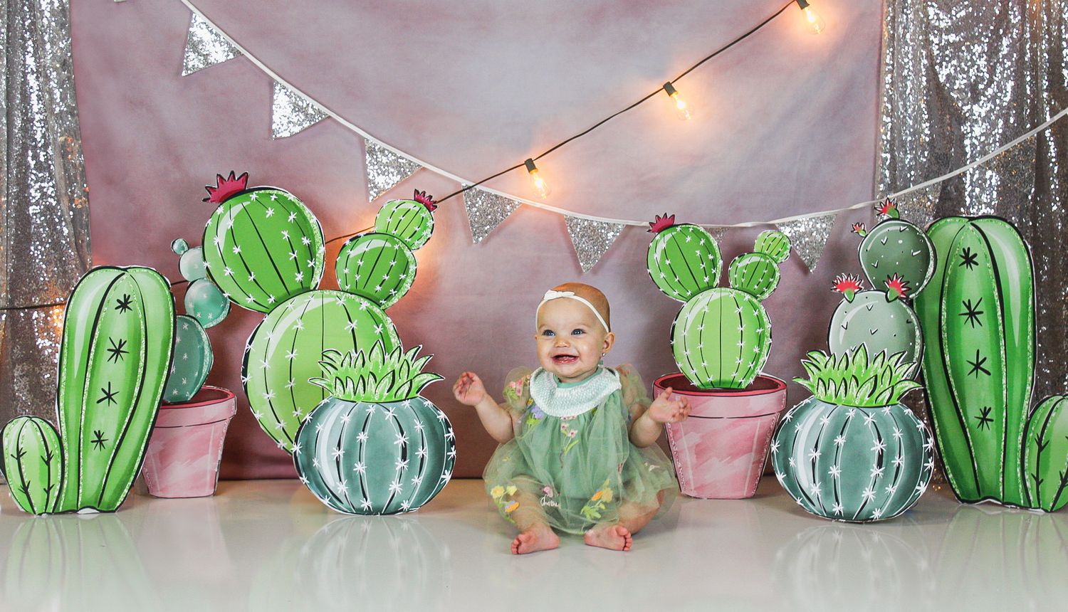 Whimsical desert-themed photo setup with paper cacti decorations and twinkling lights.