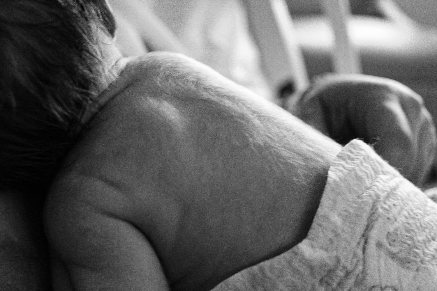 Close-up black and white shot of a newborn baby's head resting on a blanket.