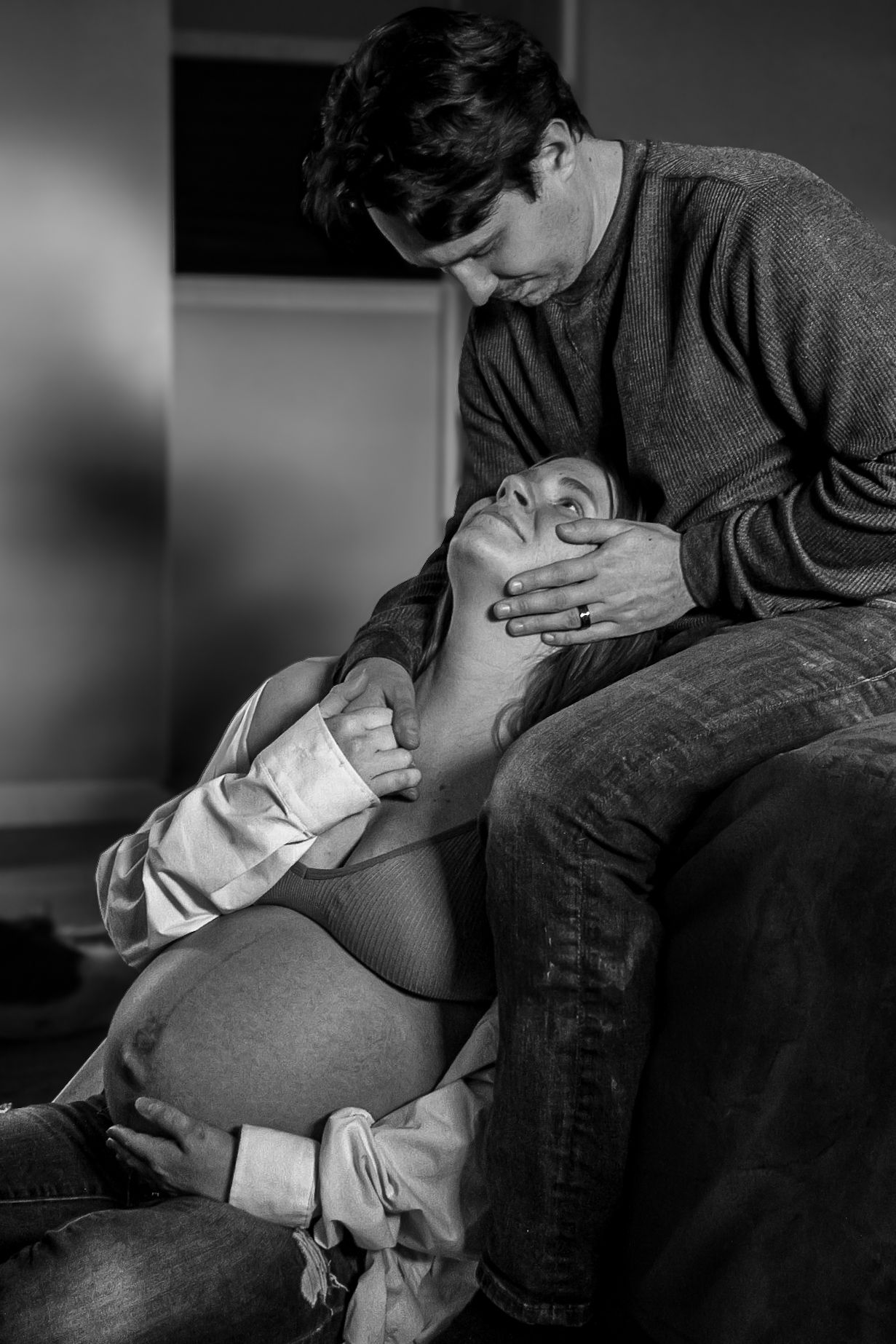 A tender black and white moment between a couple during pregnancy.