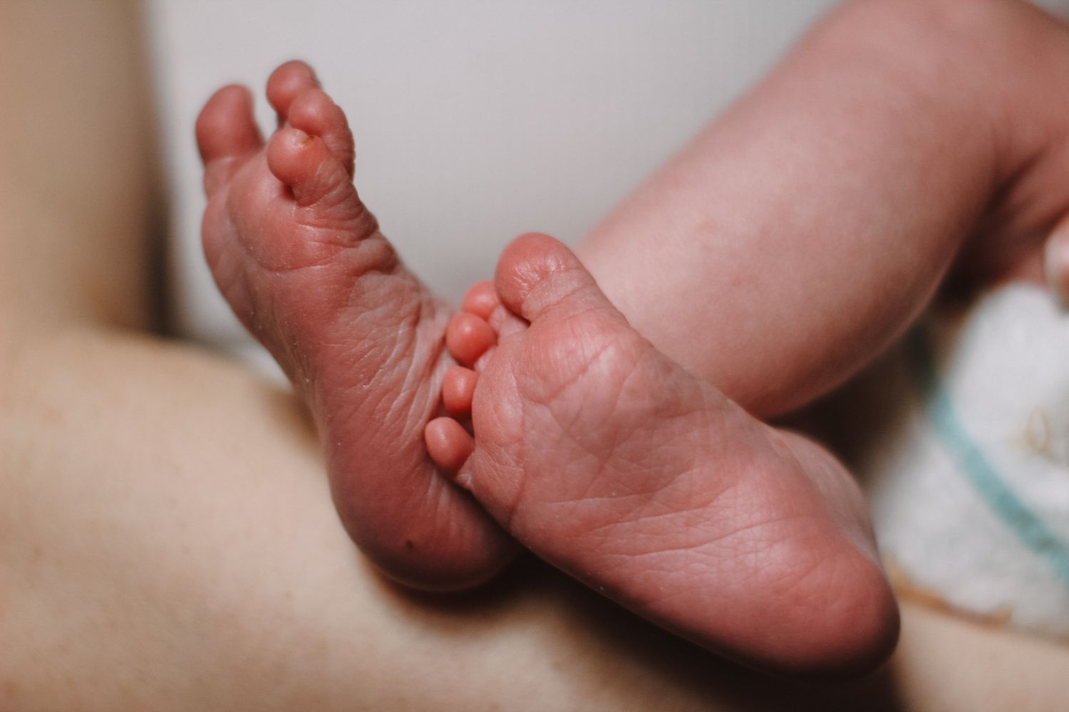 Close-up of a newborn baby's tiny feet against a light background.