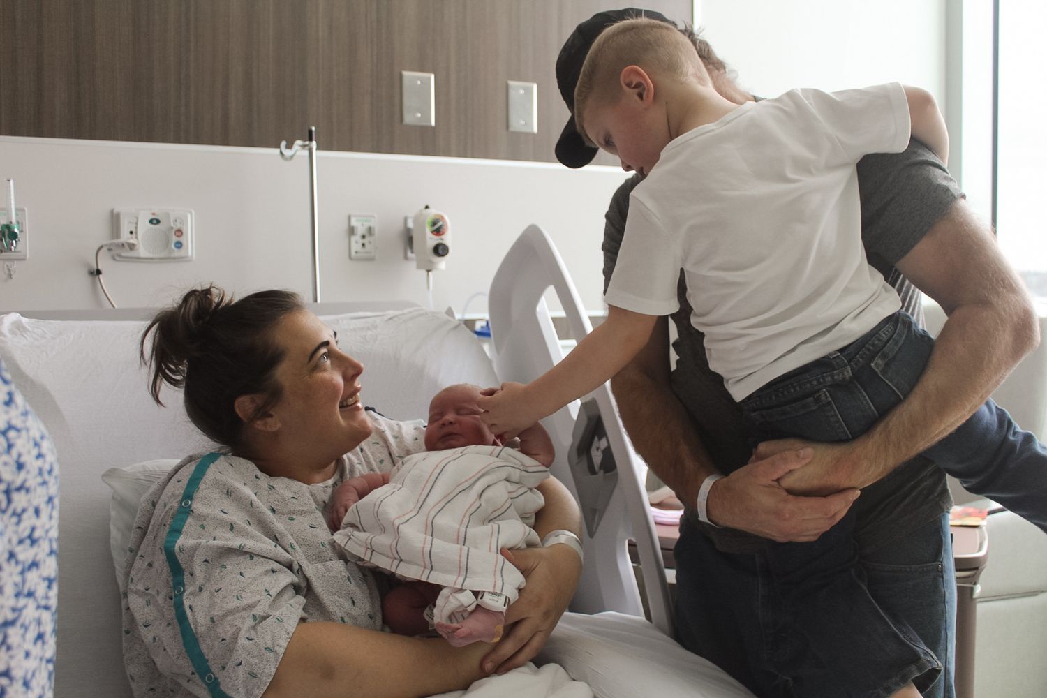 Group of visitors surrounding a hospital bed in a medical room.