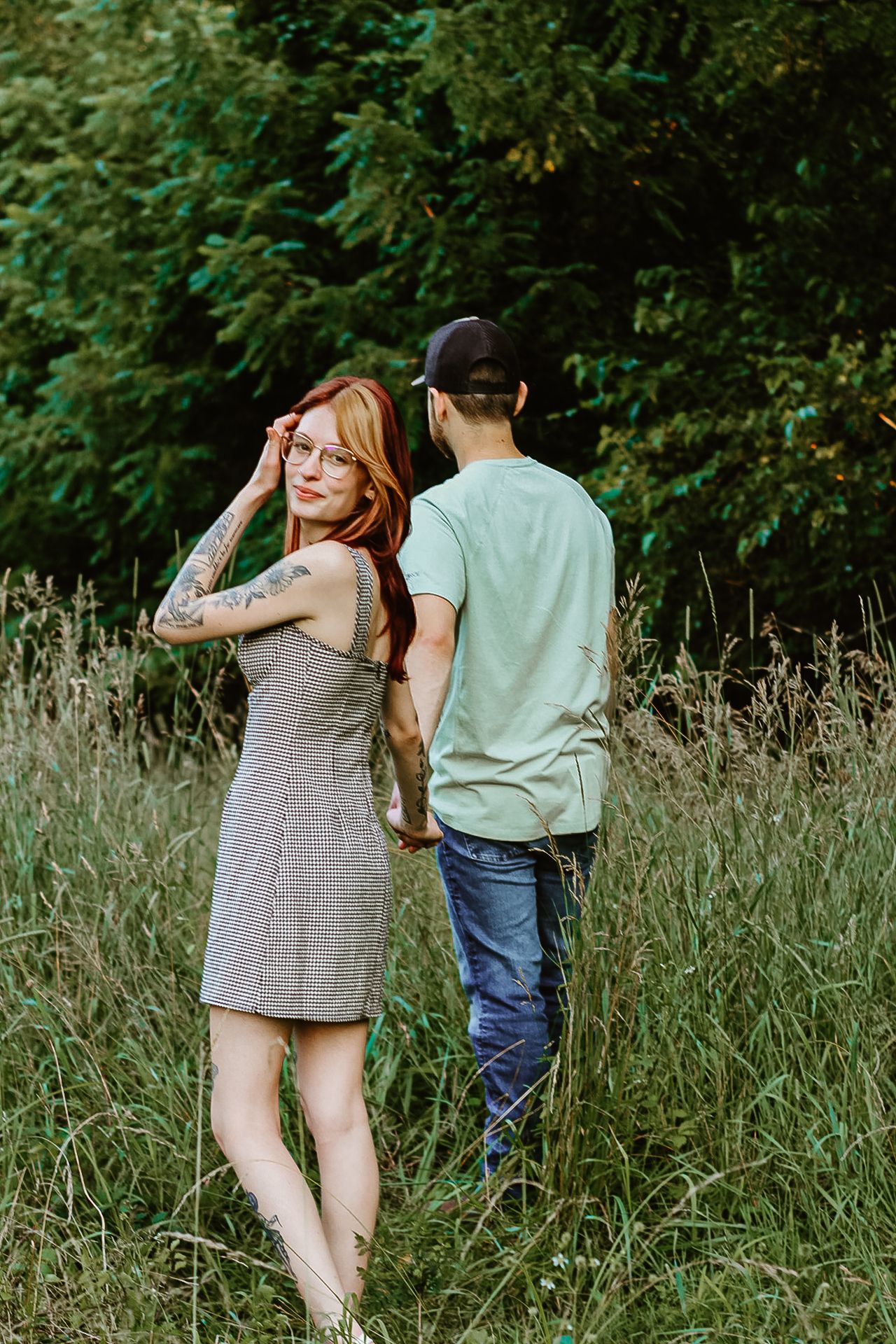Couple walking through tall summer grass in late afternoon light.