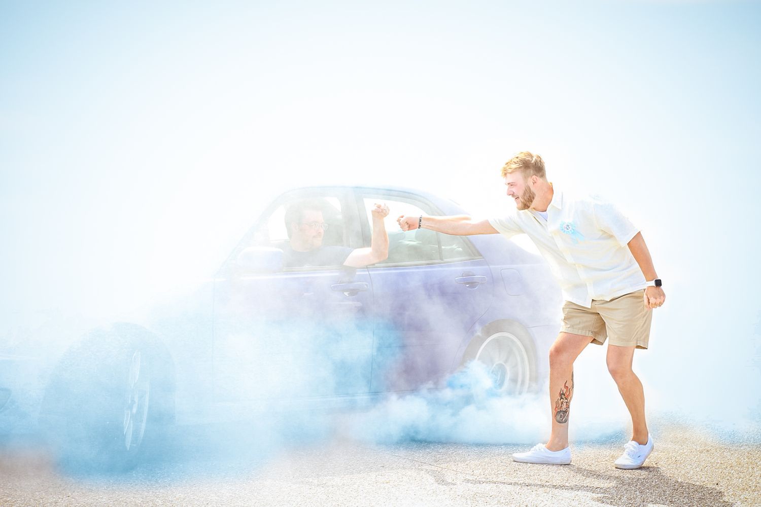 People celebrating outdoors with colorful smoke effects against bright sky.