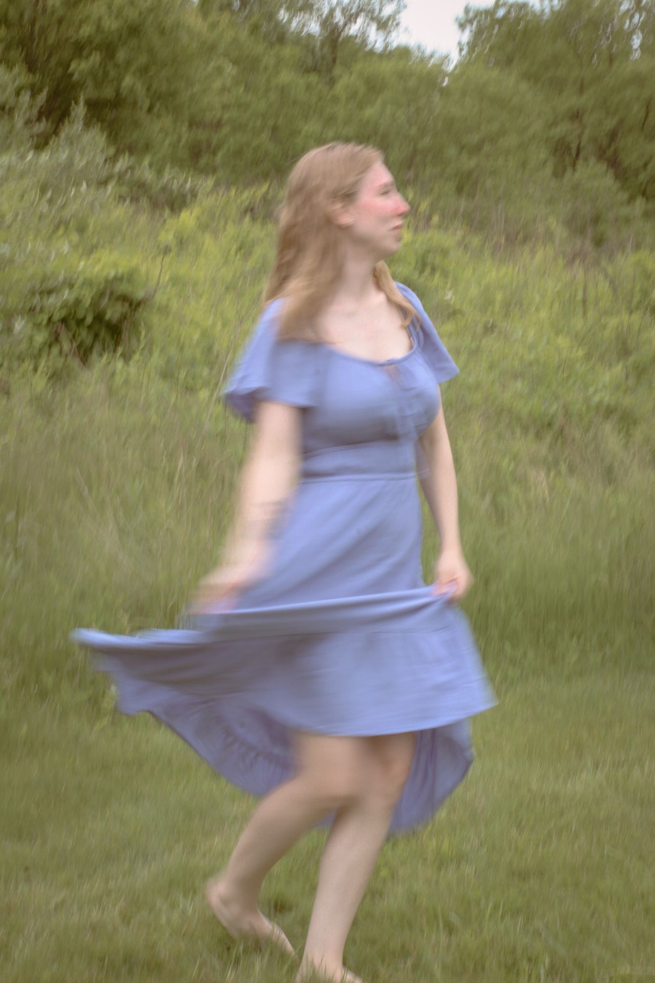 A motion sequence showing a woman in a light blue dress twirling and spinning in a grassy outdoor setting.