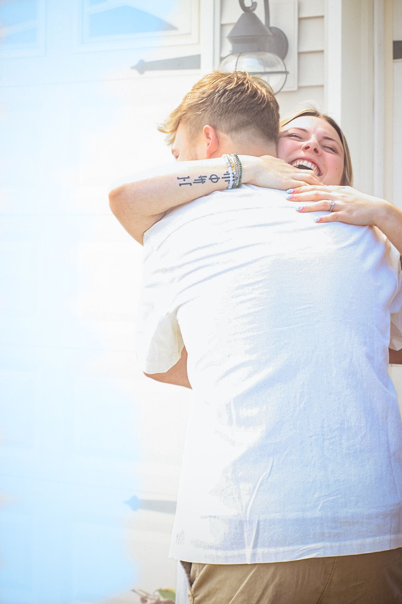 People sharing emotional embraces during outdoor celebration with bright backlighting.
