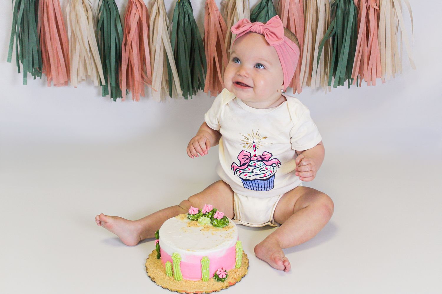 First birthday cake smash scene with colorful tassels and festive decorations.