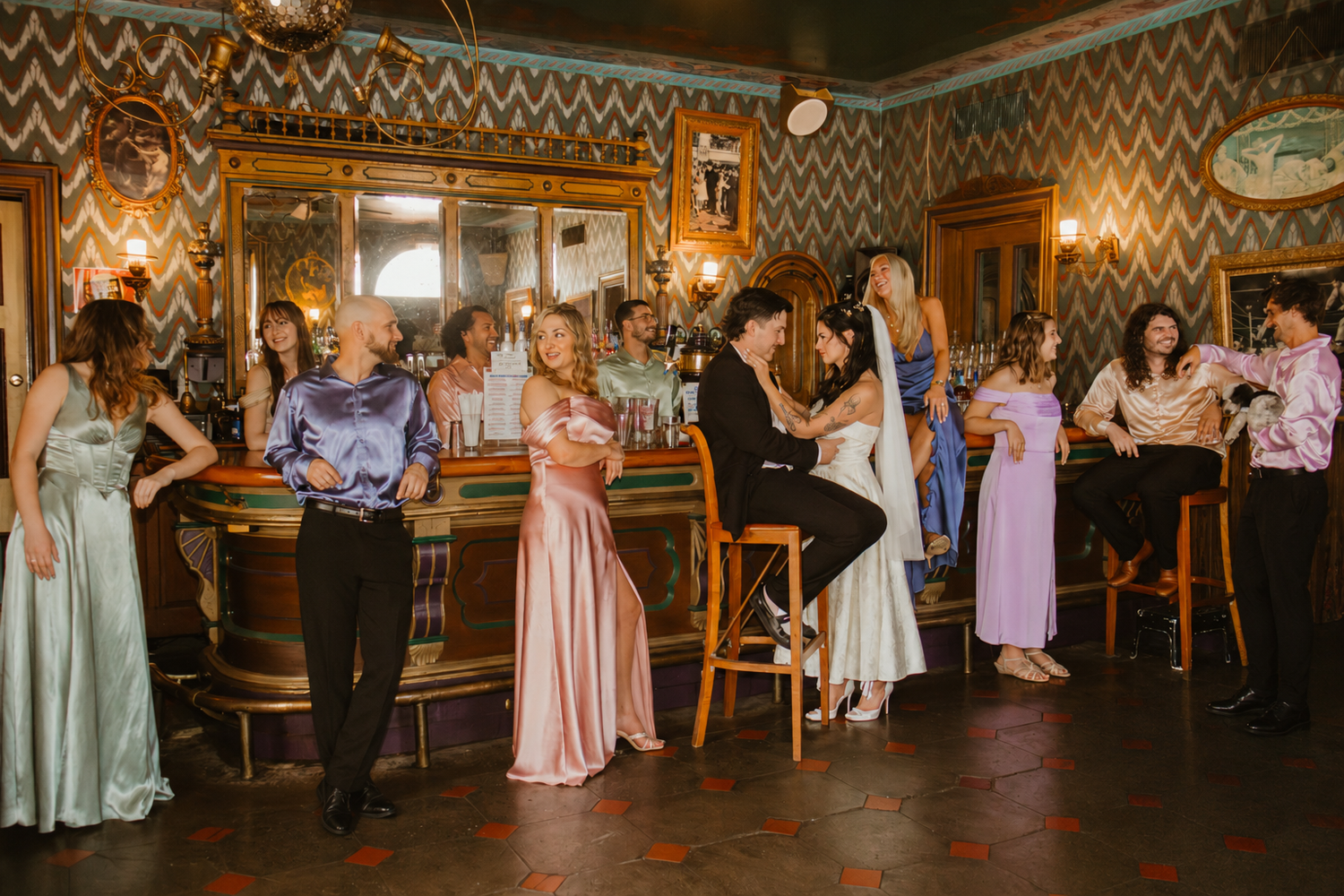 Elegant guests socializing at an ornate bar with vintage decor during a formal event or wedding reception.
