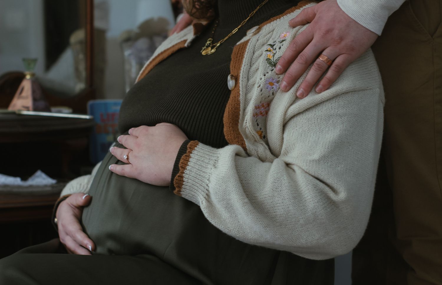 Close-up of hands resting gently on neutral-colored clothing.