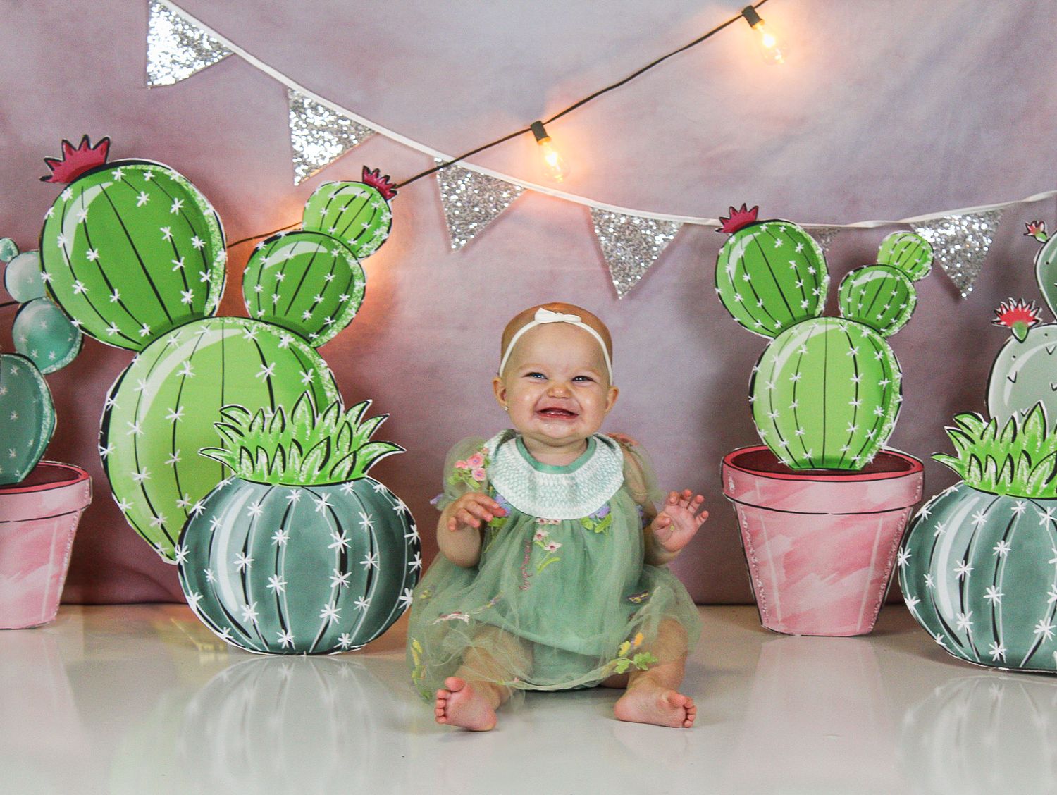 Charming desert scene backdrop with handcrafted paper cacti and silver bunting decorations.