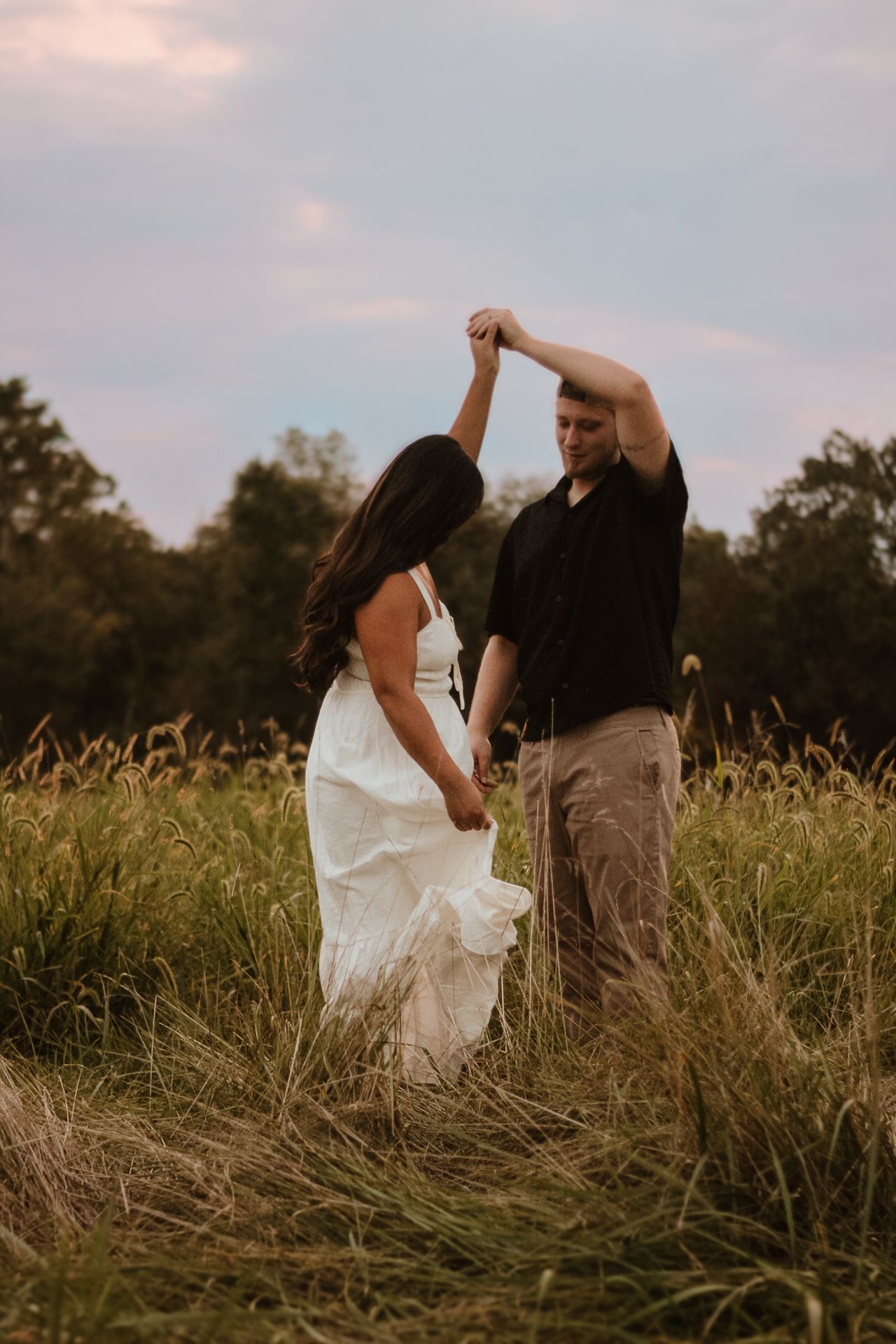 A couple dances together in a golden field at sunset, creating a romantic silhouette against the warm sky.