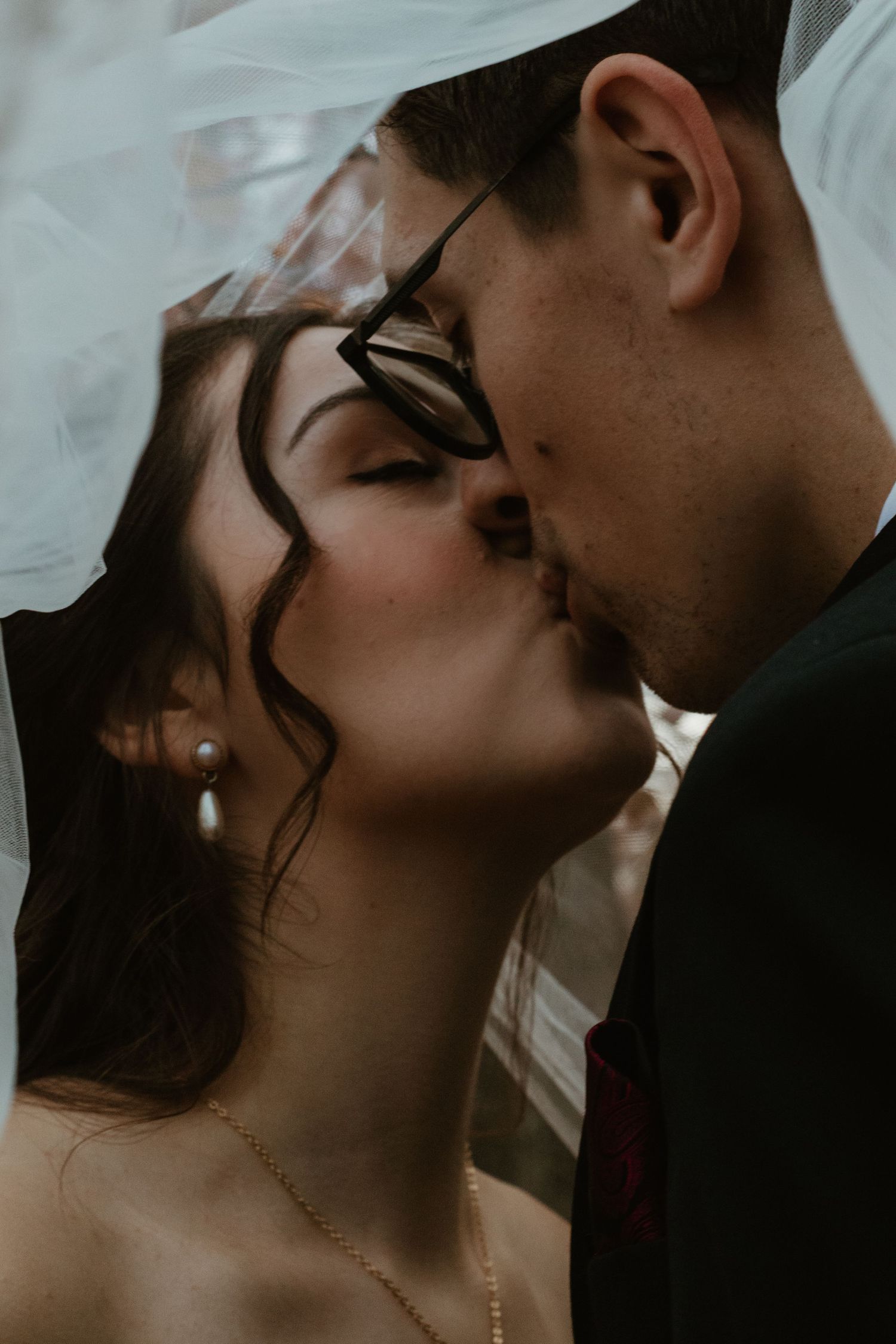 Romantic wedding couple sharing intimate kisses in moody black and white portrait series.