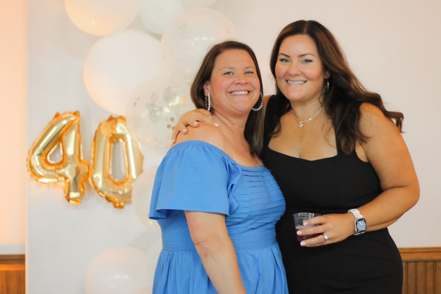 Friends posing together at a party with gold number balloons in the background.