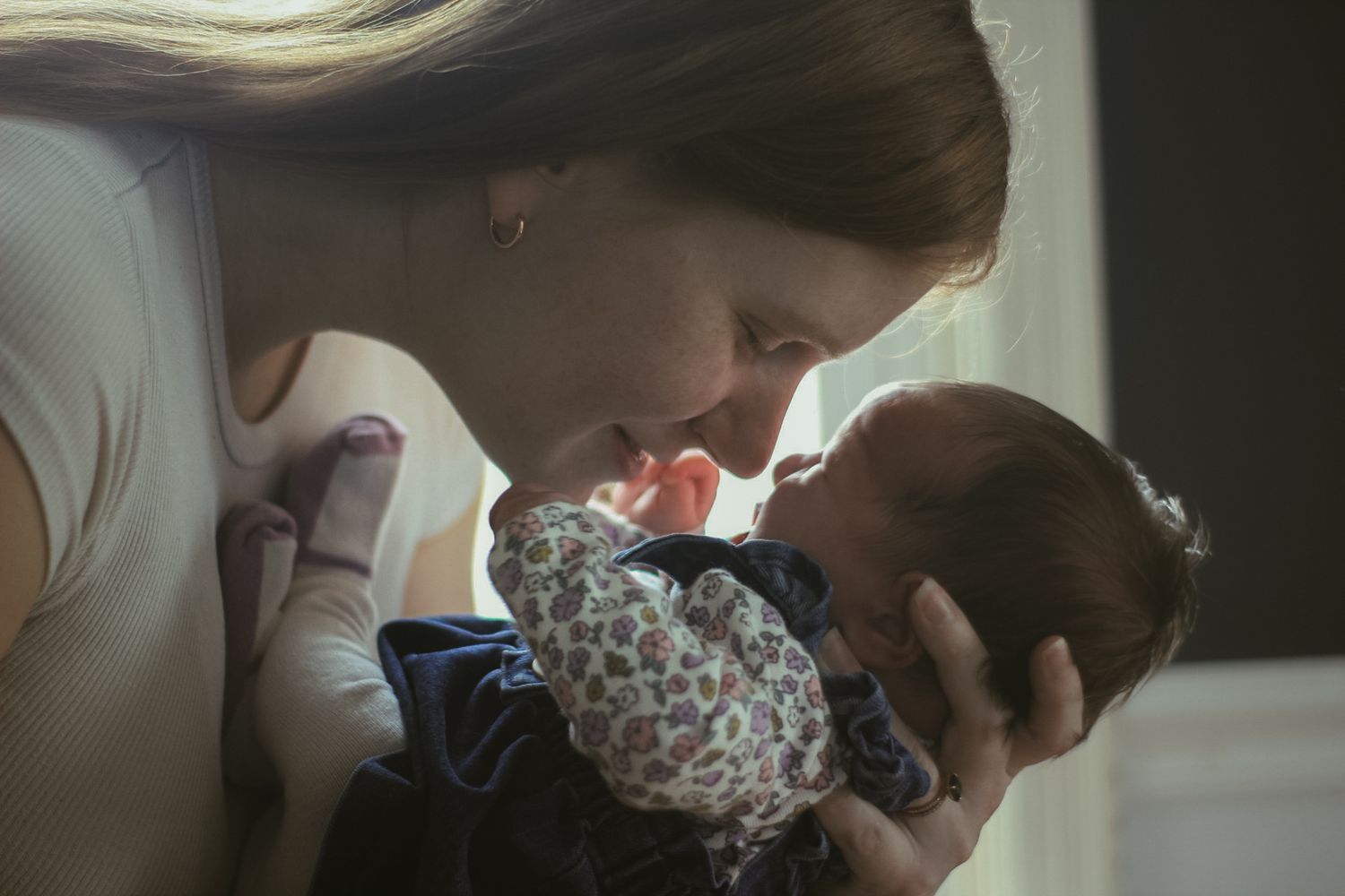 An intimate family moment captured in soft lighting by a window.