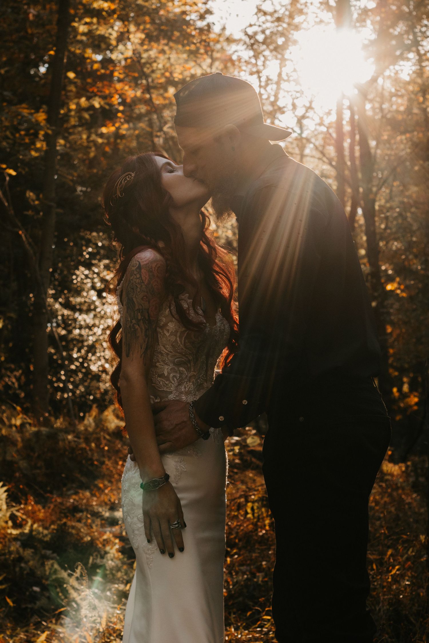 A romantic couple embraces in a sunlit autumn forest with golden light streaming through the trees.