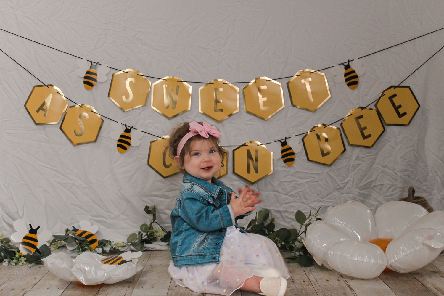 Bee-themed party decorations with hexagonal banners and white balloon arrangements.