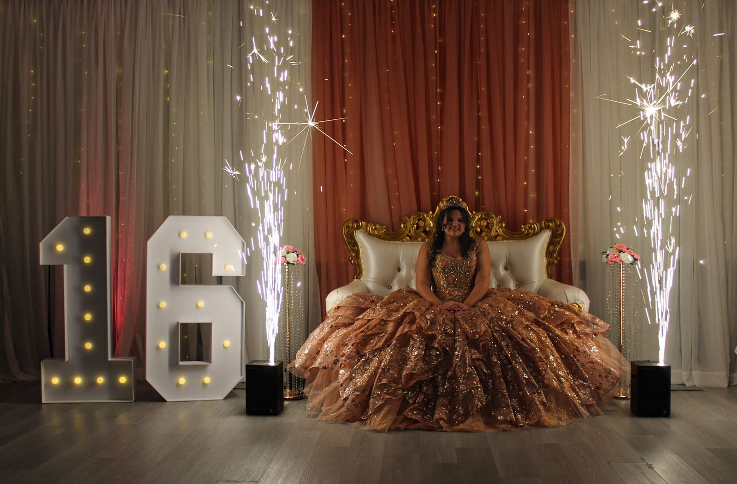 Special event venue setup featuring sparkling fountains and rose gold decor against dramatic lighting.