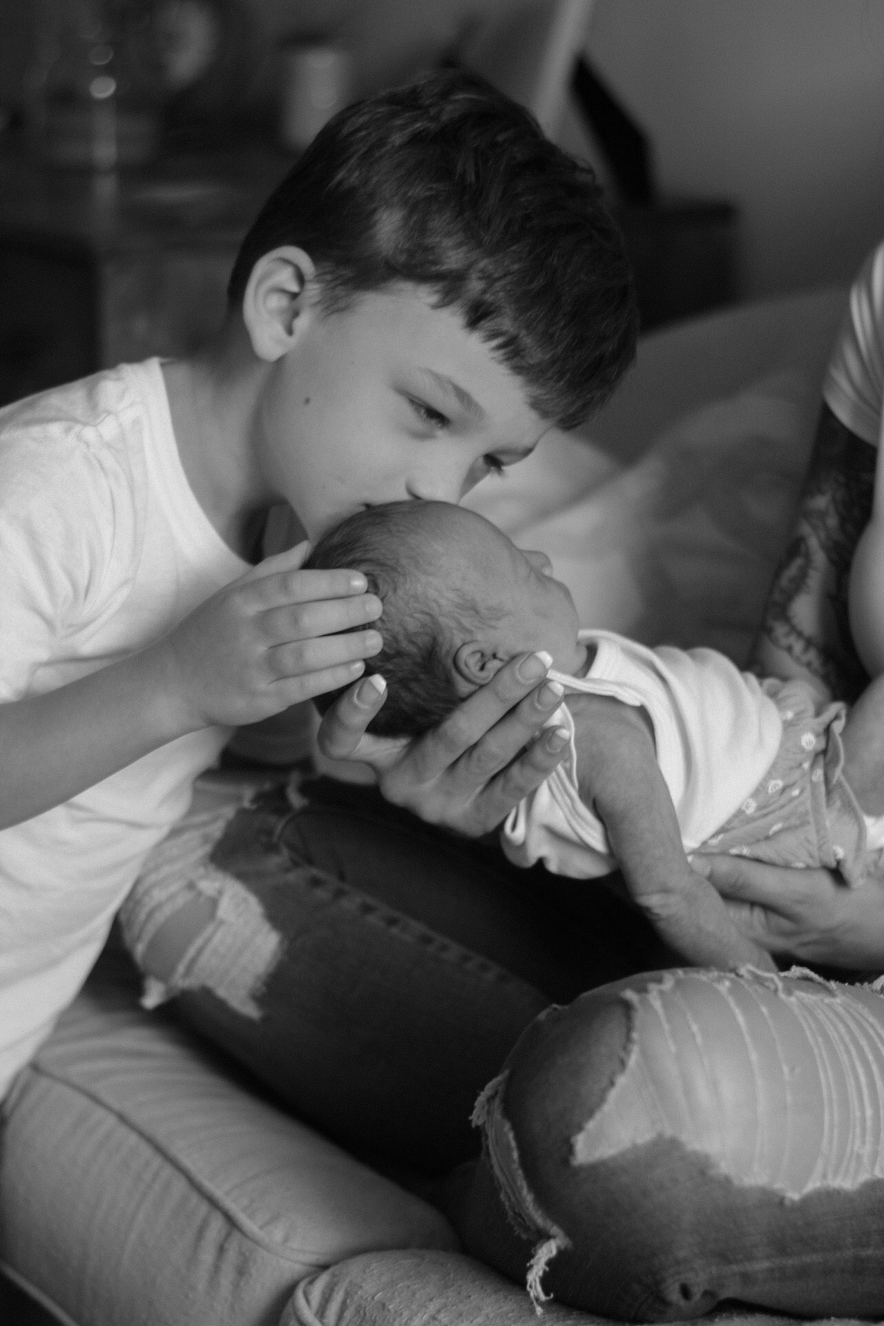Black and white sequence capturing gentle parent-child interactions on a couch.