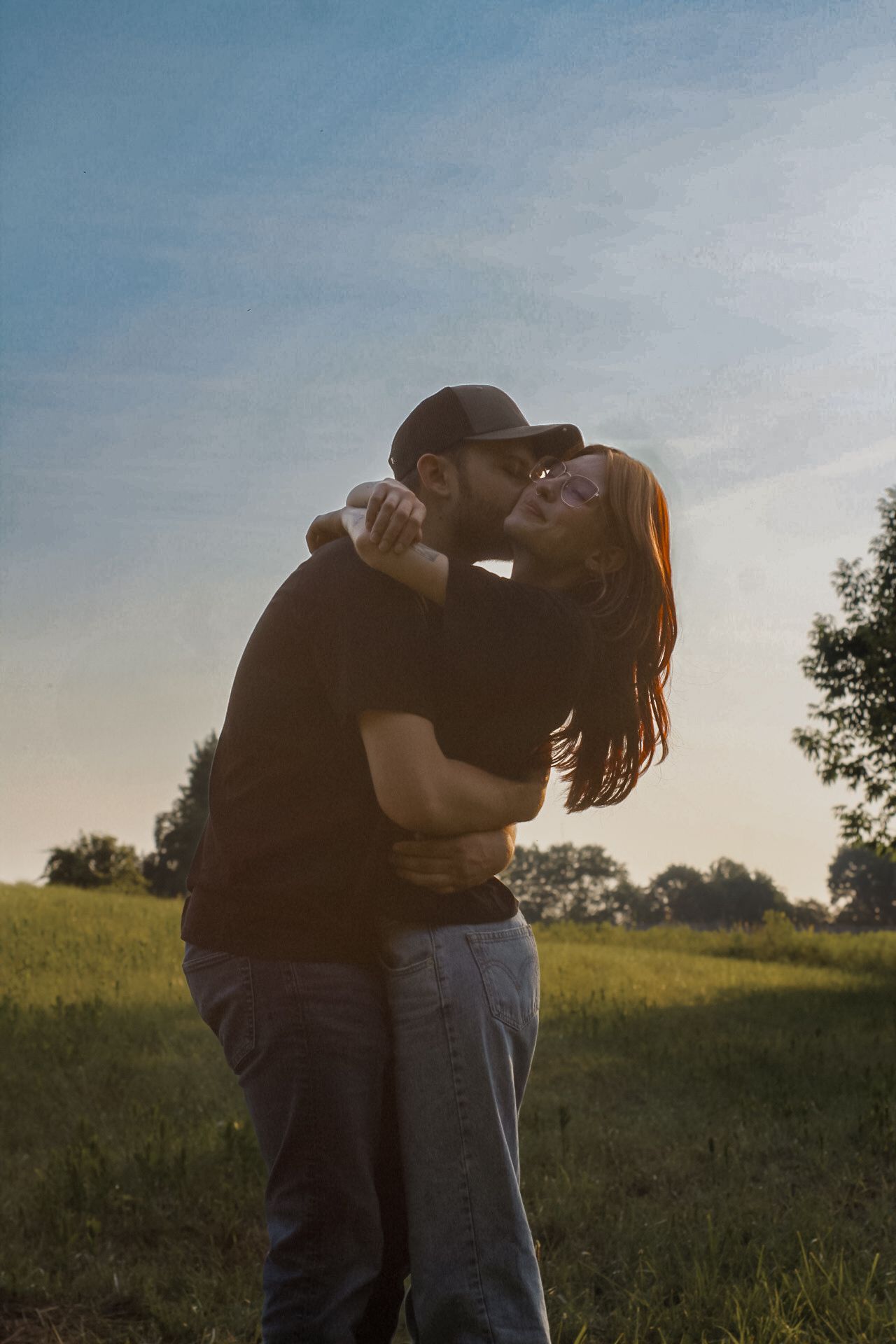 Silhouetted couple embracing in a golden sunset field.