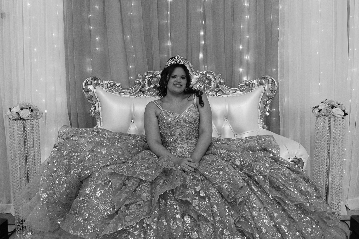 Black and white portrait of guest in glittering ballgown seated on elegant tufted throne.