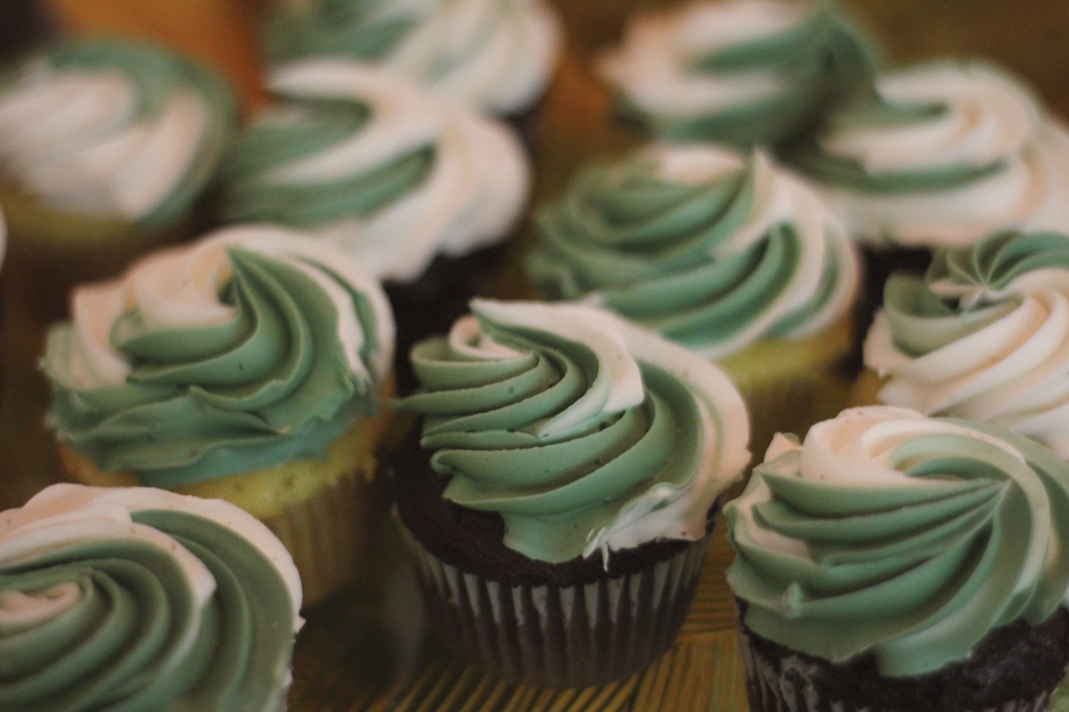 Close-up of mint green and white swirled frosting on chocolate cupcakes.
