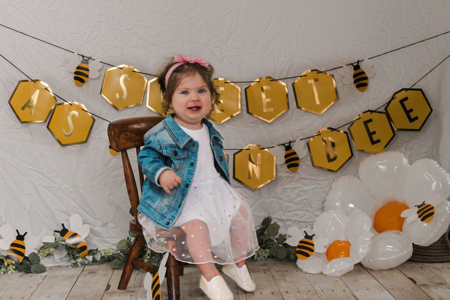 Birthday celebration with honey bee themed banner and white balloons.