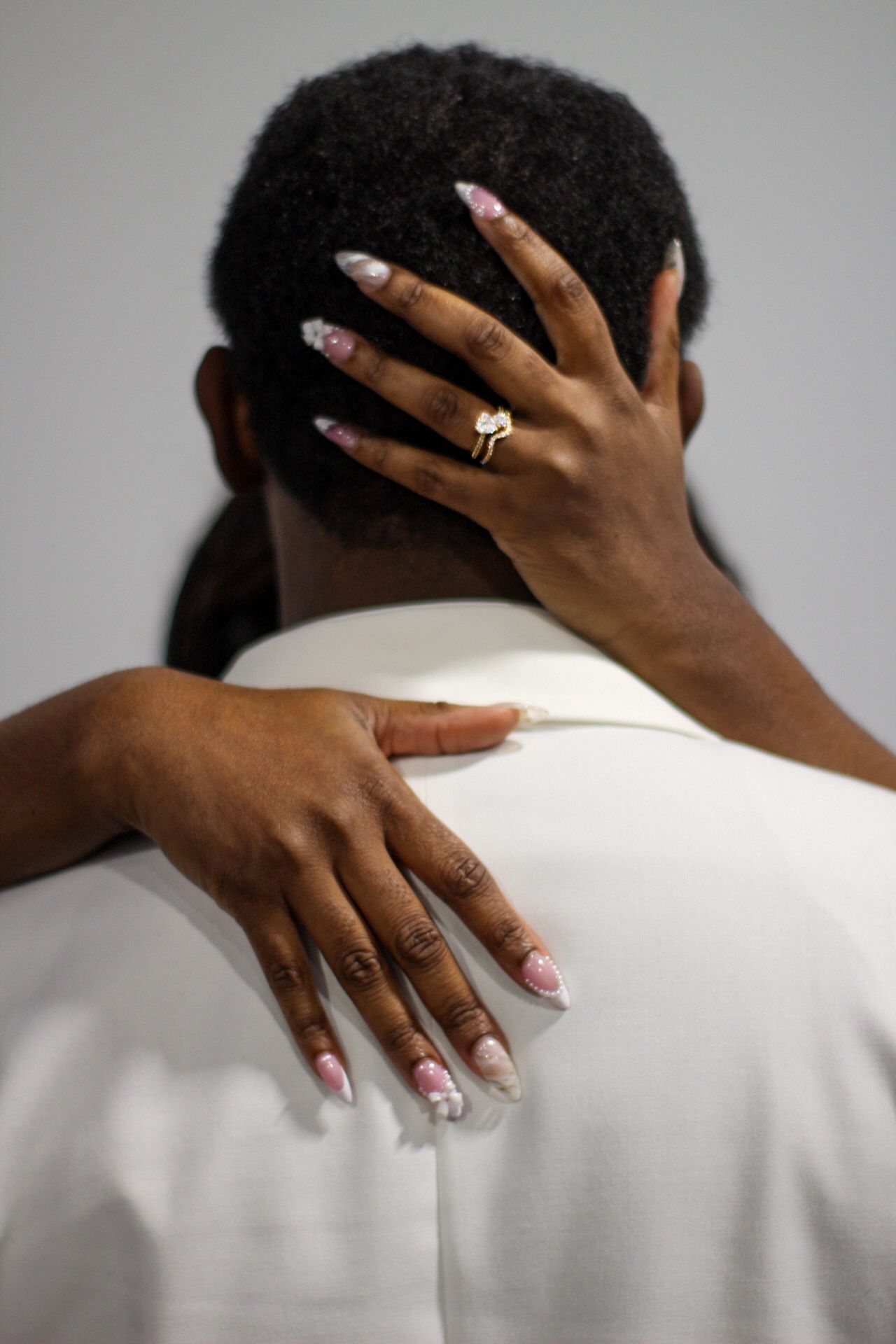Artistic wedding photo showing hands with engagement ring and manicured nails.