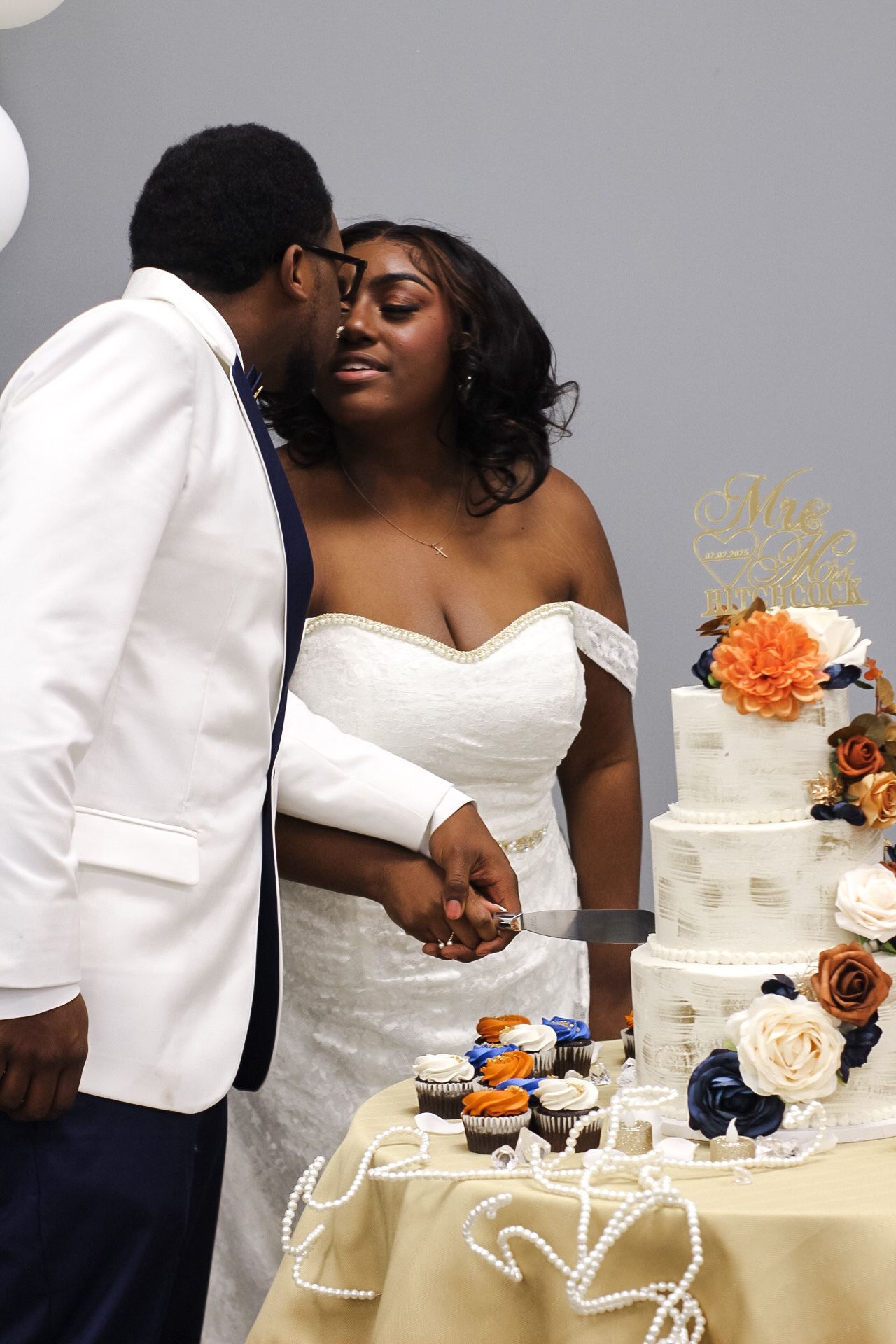 Newlyweds share a tender moment beside their elegant tiered wedding cake.
