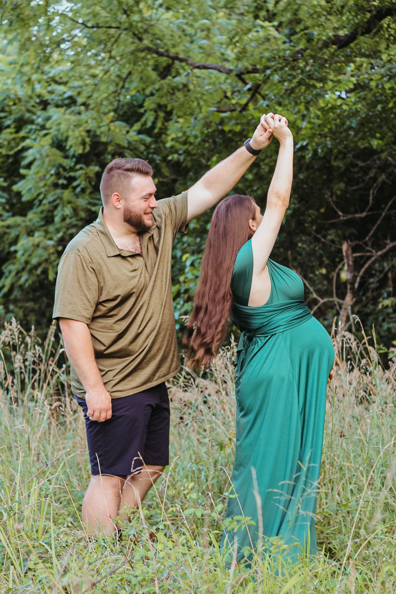 A couple dances together in a field of tall grass on a sunny summer day.