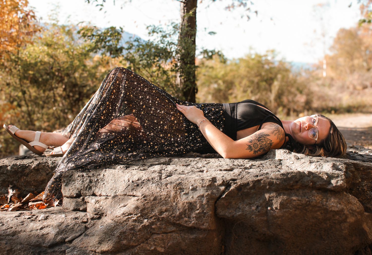 Artistic outdoor photo of someone lying on a tree trunk during golden hour.