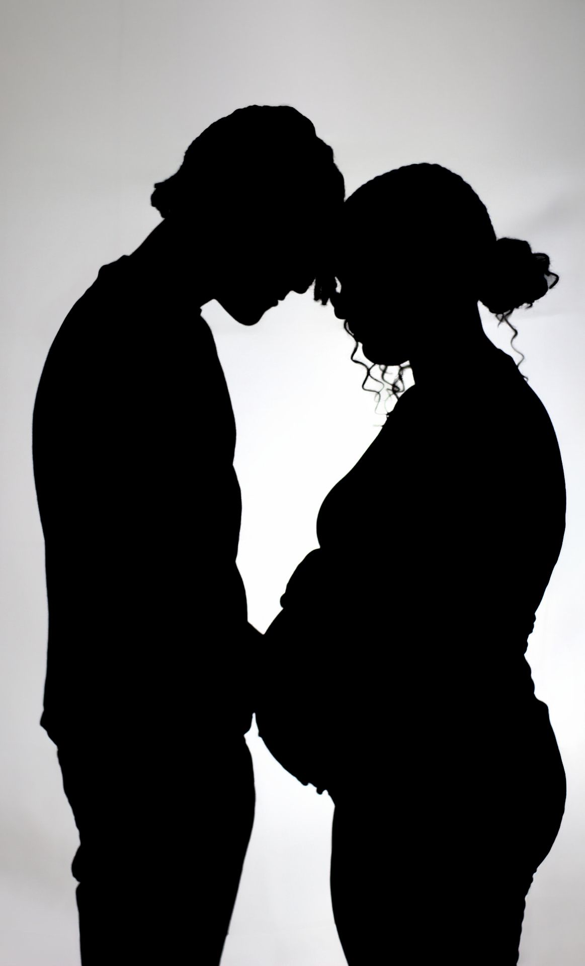 Intimate silhouette portrait of expecting couple in tender moment.