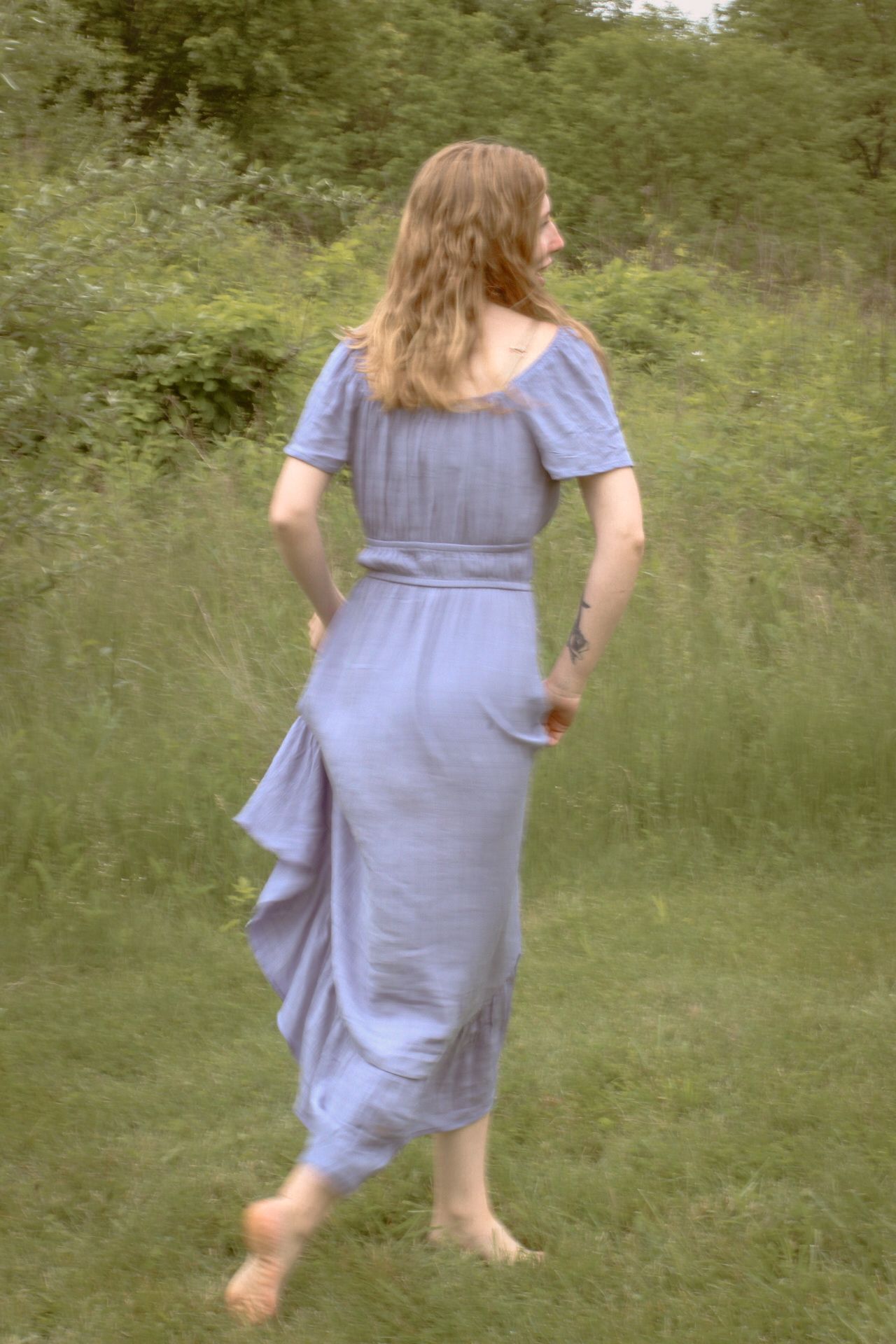 A motion sequence showing a woman in a light blue dress twirling and spinning in a grassy outdoor setting.