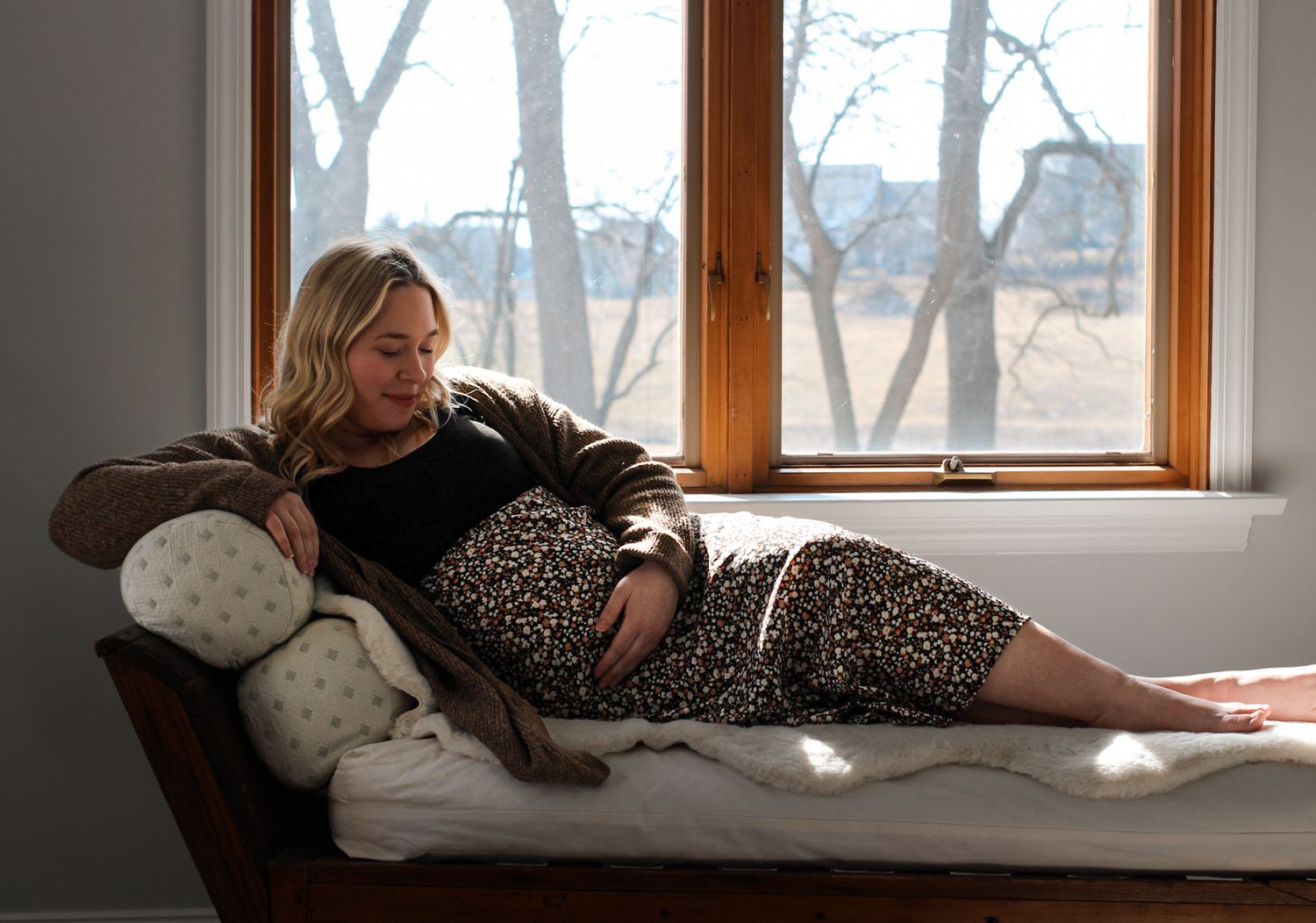 Person lounging on couch wearing floral dress and brown cardigan.