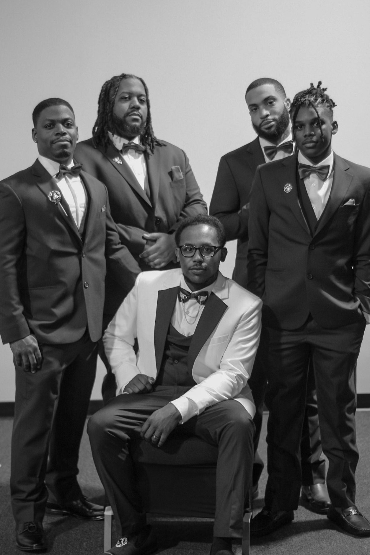Formal group portrait of groomsmen in tuxedos and bowties.