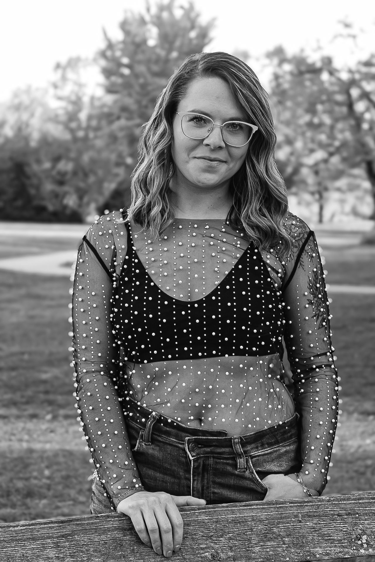 Black and white portrait featuring a sparkly mesh top and glasses in an outdoor setting.