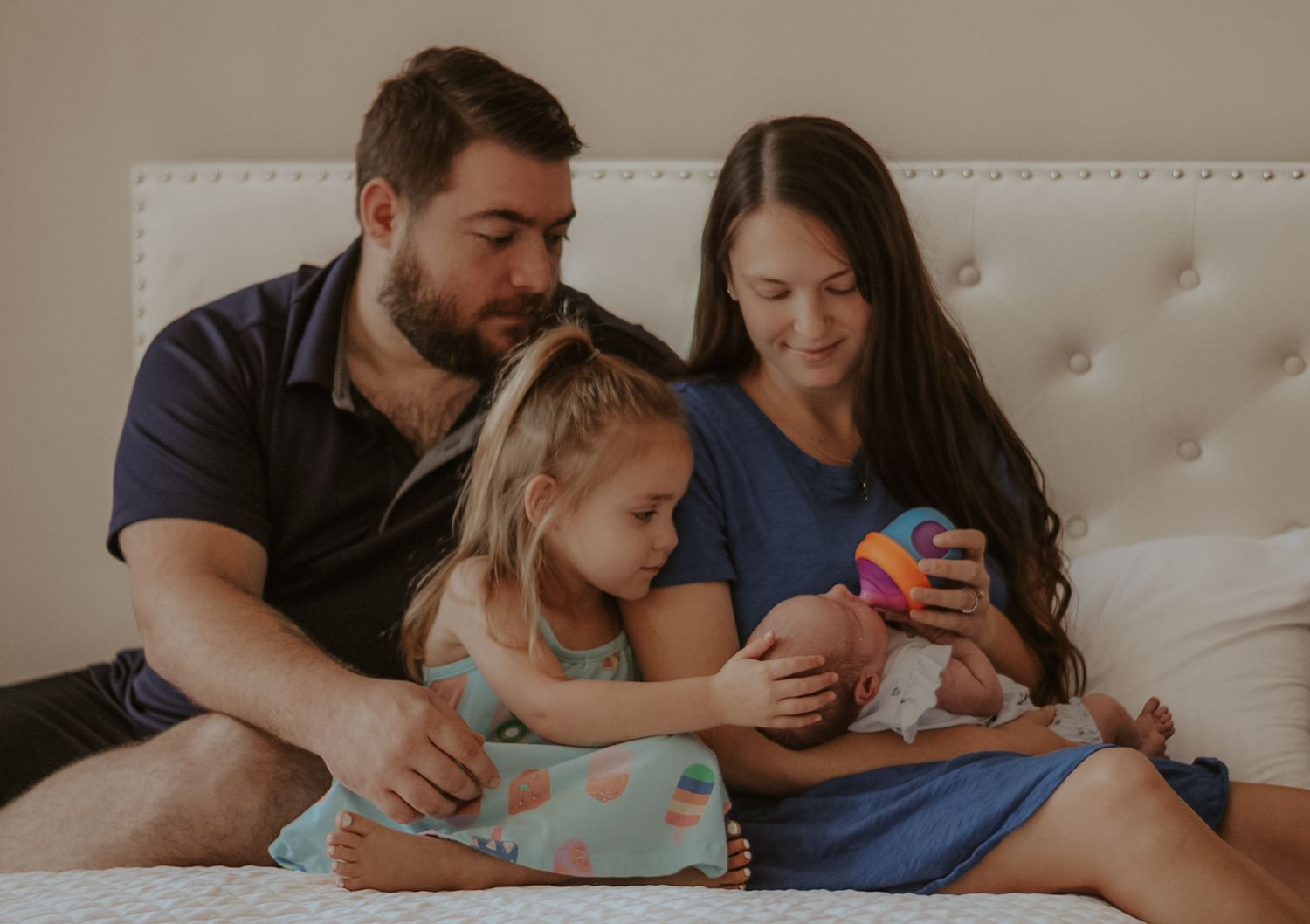Family relaxing together on white couch while reading books and spending quality time at home.