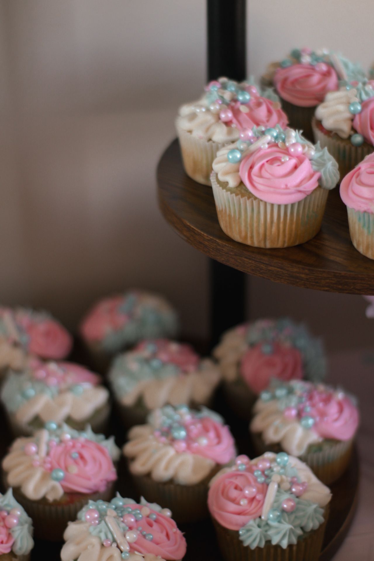 Close-up of cupcakes decorated with pink and blue swirled frosting and pearl sprinkles.