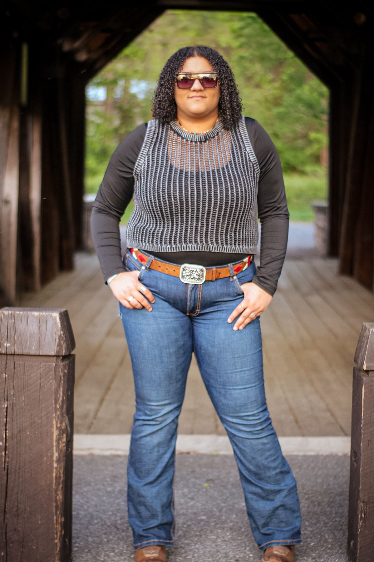 Fashion portrait in covered wooden walkway wearing striped top and blue jeans.
