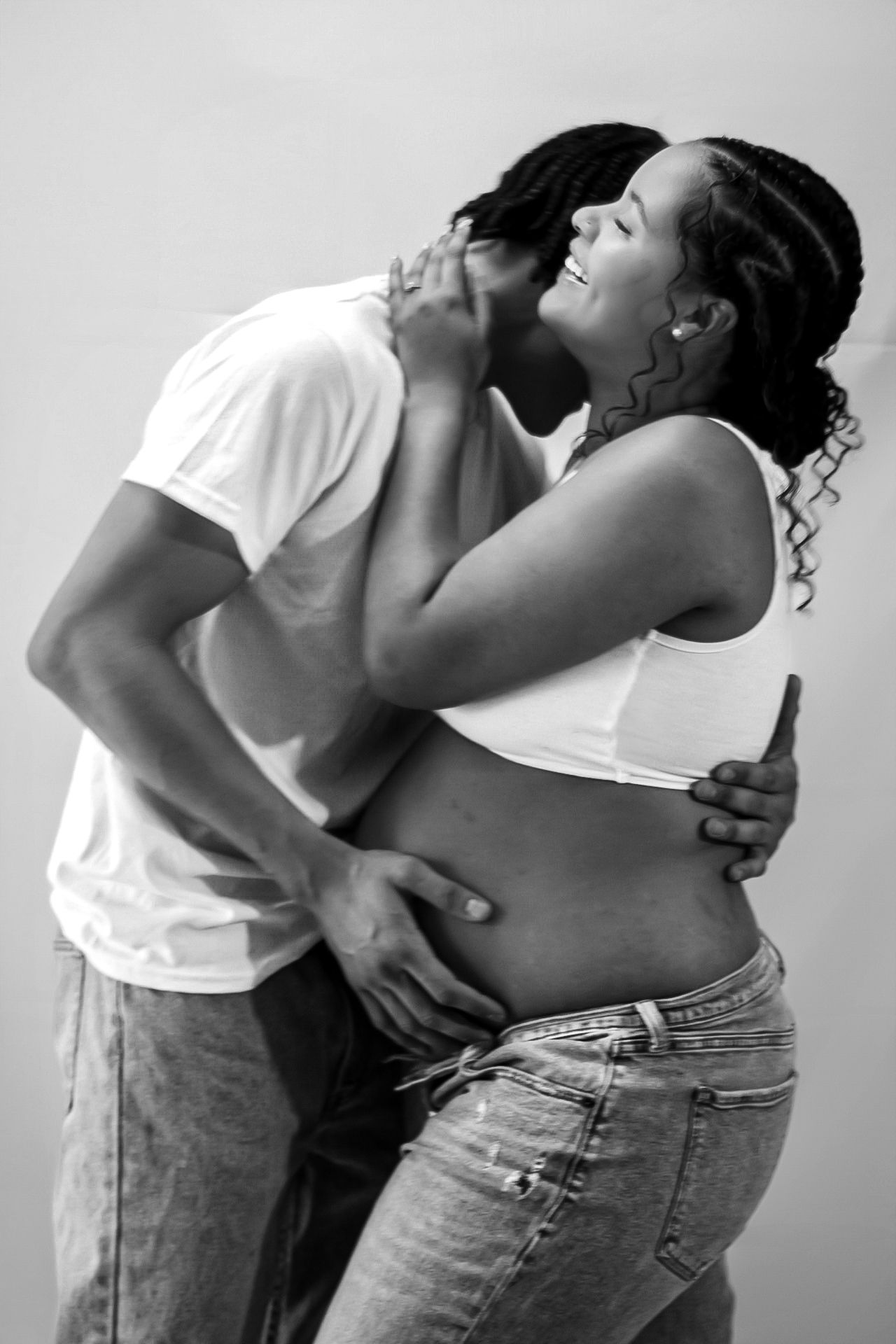 Intimate black and white maternity photo showing couple's joyful embrace.