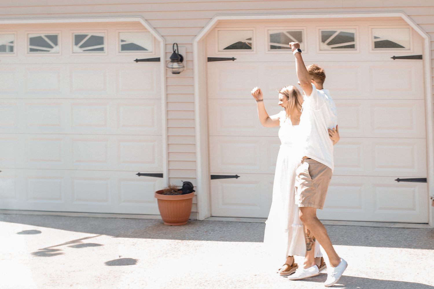 White garage doors and car parked in driveway with pink and blue smoke effects.