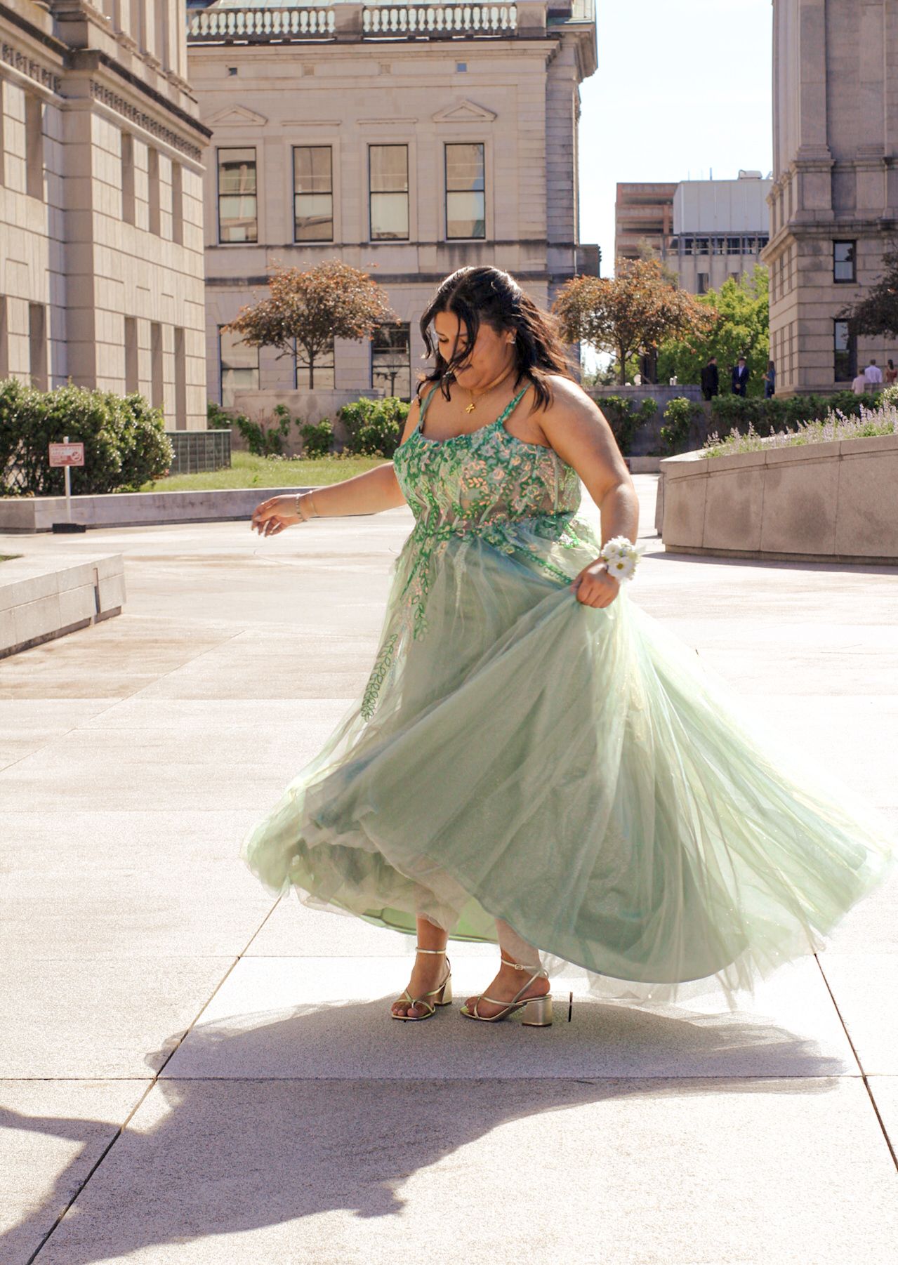 A flowing mint green ballgown twirls gracefully across a stone courtyard.