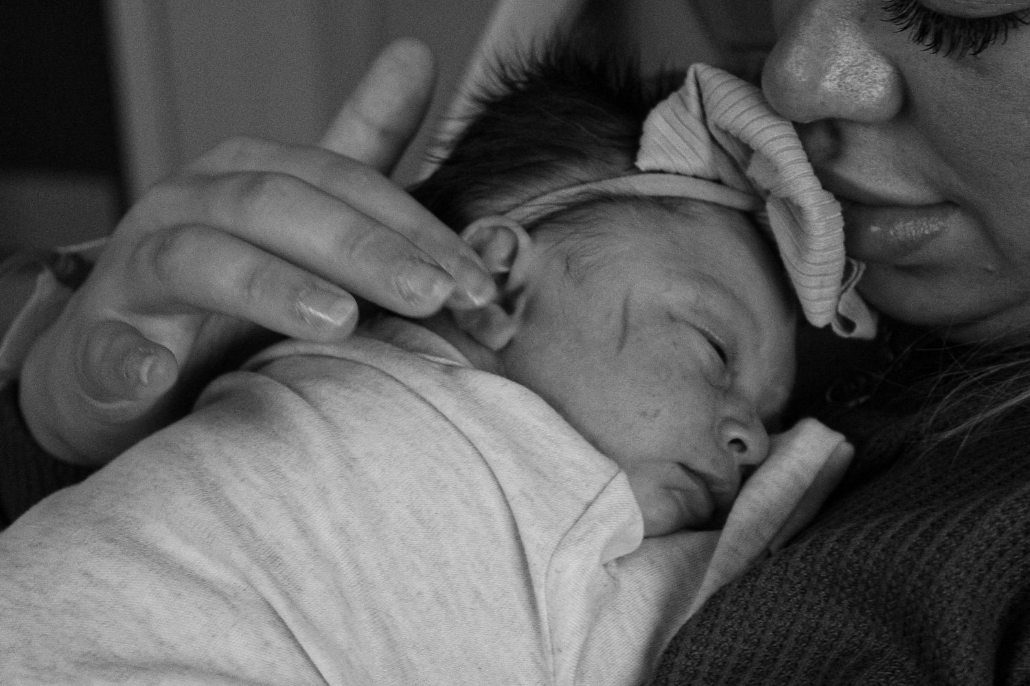 Tender black and white moment of a mother holding her sleeping newborn close.
