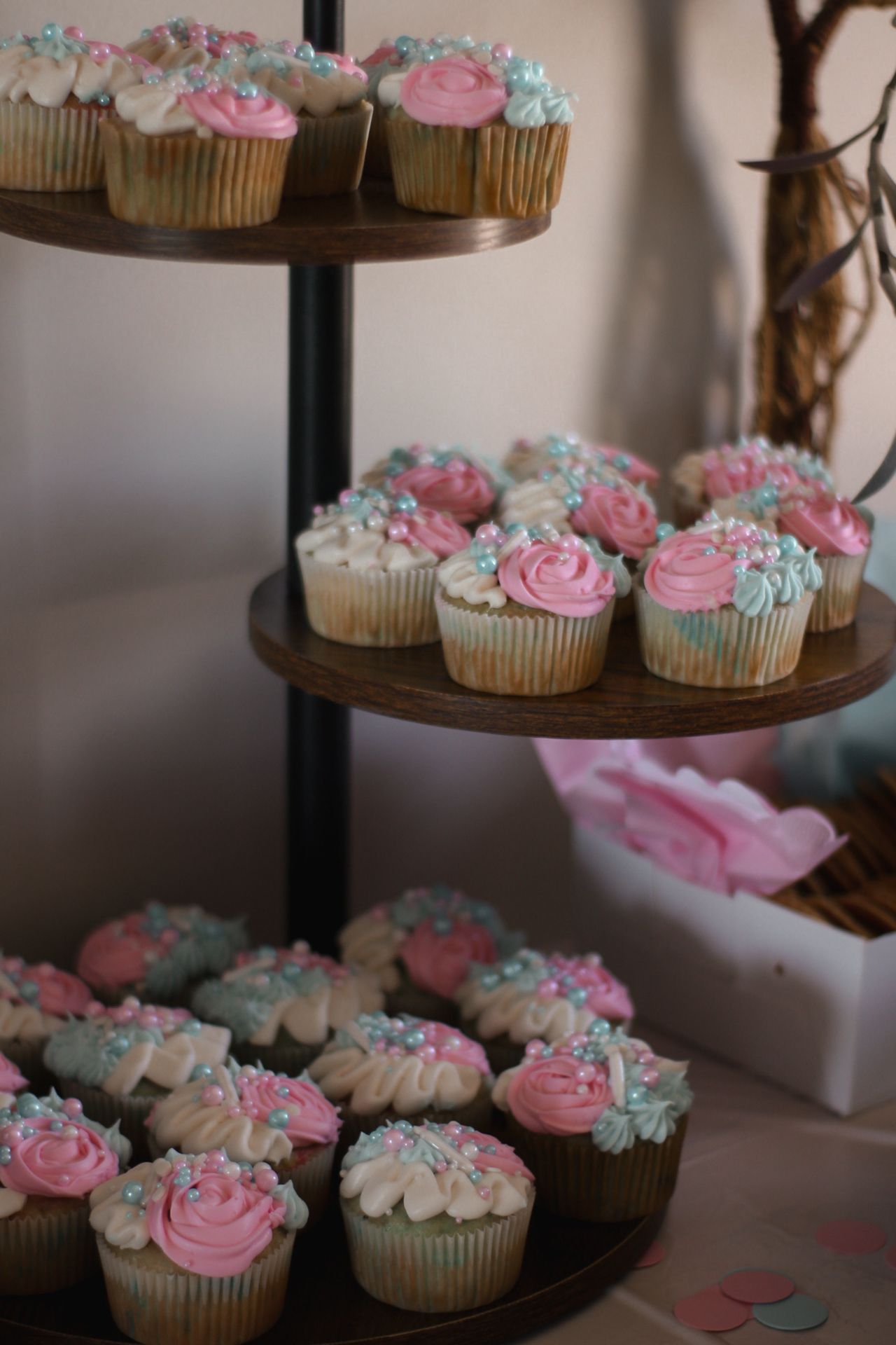 Tiered display of cupcakes decorated with pink and blue frosting and sprinkles.