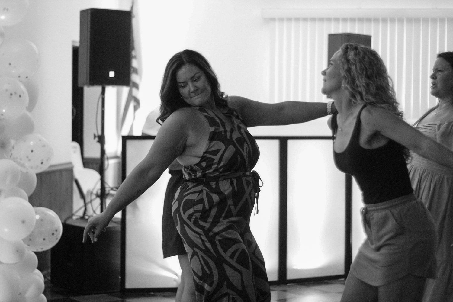 People enjoying themselves while dancing at a celebration in black and white.