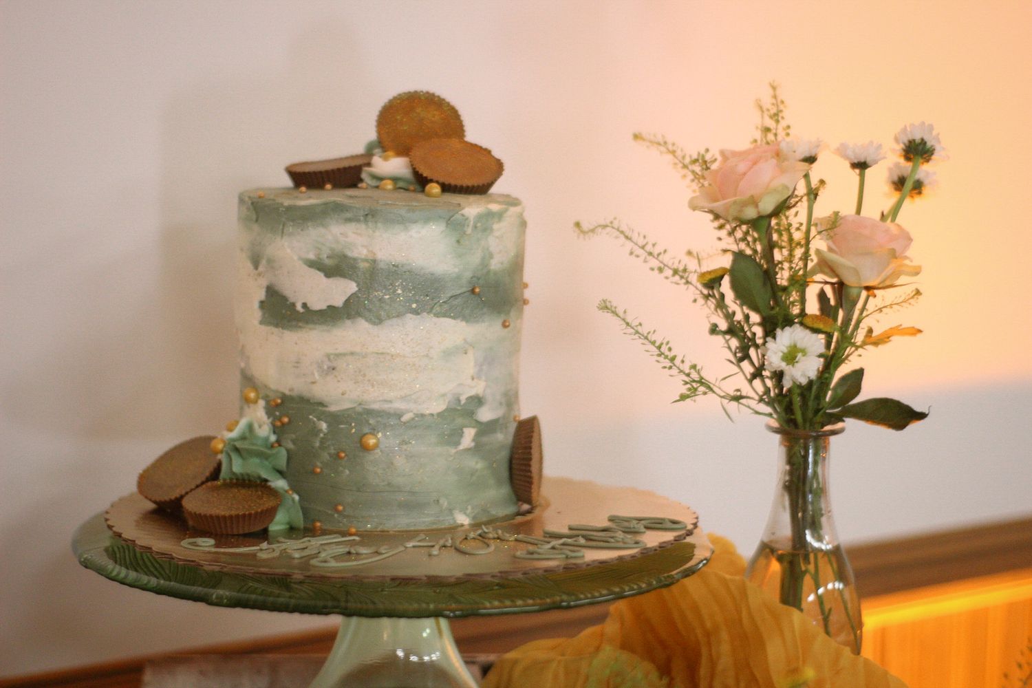 Elegant celebration setup with blue and white cake, fresh flowers, and rustic decor.
