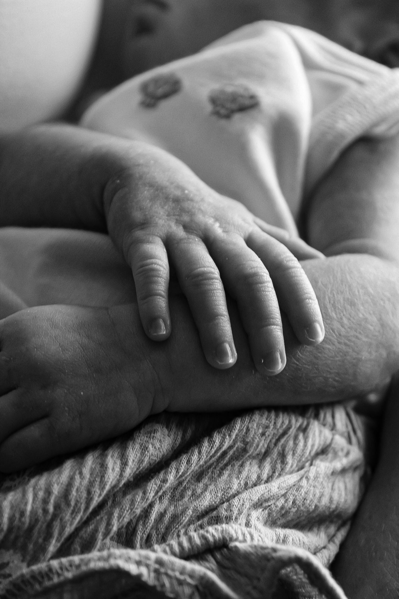 Artistic black and white macro shots of small hands resting on textured fabric.